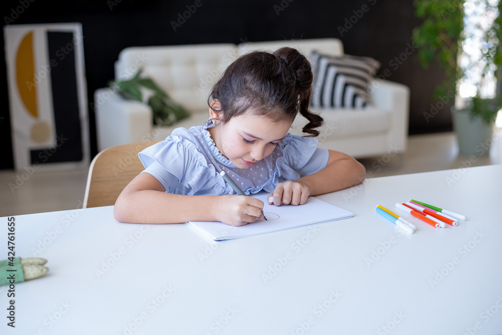 Beautiful young schoolgirl drawing at a white table in her room, home learning concept Beautiful young schoolgirl drawing at a white table in her room, home learning concept