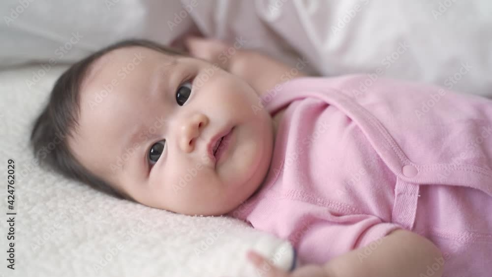 asian baby infant laying down on white soft bed happy and smile. 3 months old baby facial expression. asian baby infant laying down on white soft bed happy and smile. 3 months old baby facial expression.
