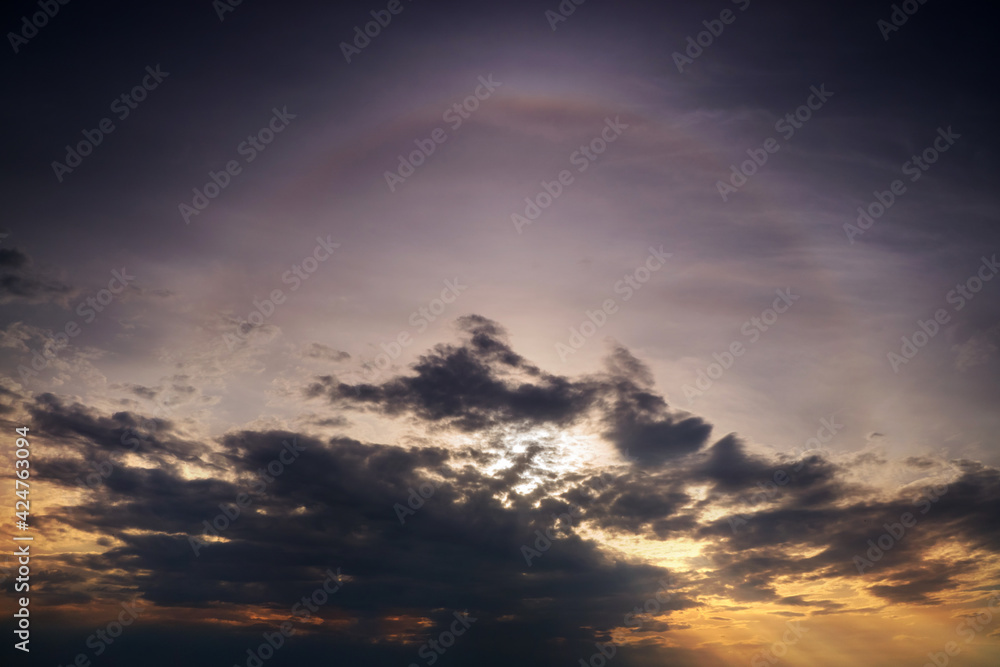 A solar halo in the evening sky among dark rain clouds.