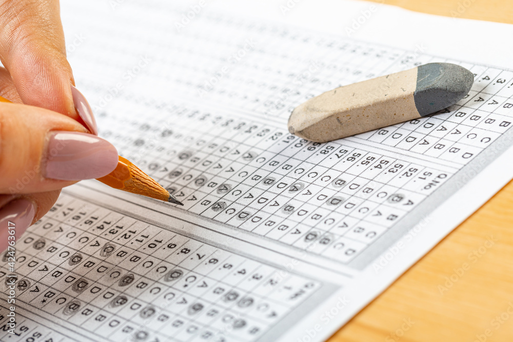 Obraz premium The student fills in the answers to the test in the exercise and examination paper with a pencil. education concept.