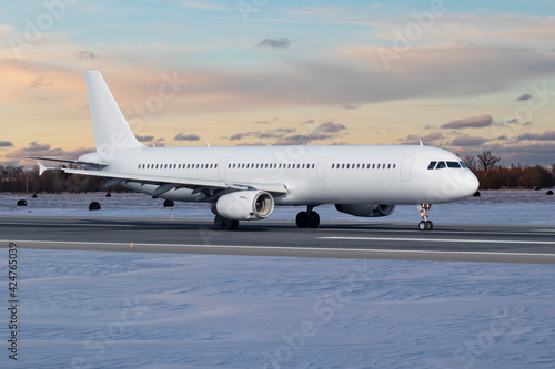 Travel image of a big white passenger airplane on a runway before takeoff in winter