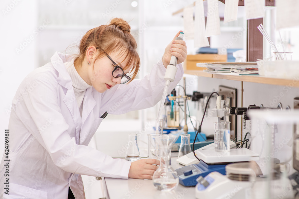 A laboratory assistant pours reagents into a flask using a special astomatic pipette. Assistant in the chemistry laboratory at the university A laboratory assistant pours reagents into a flask using a special astomatic pipette. Assistant in the chemistry laboratory at the university