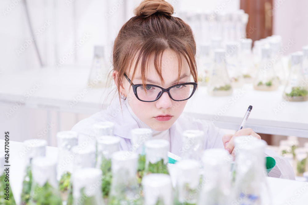 A worker in a biological laboratory fills out a report by examining plants grown in a nutrient solution in flasks. Biological research at the university A worker in a biological laboratory fills out a report by examining plants grown in a nutrient solution in flasks. Biological research at the university