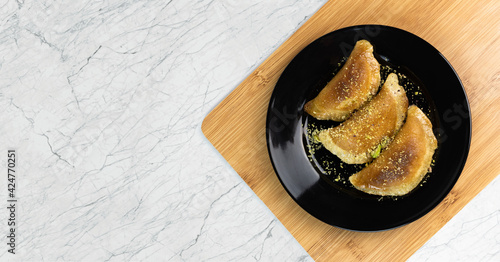 Qatayef With Pistachio On Black Plate On Marble Background. Top View, Ramadan Food. photo