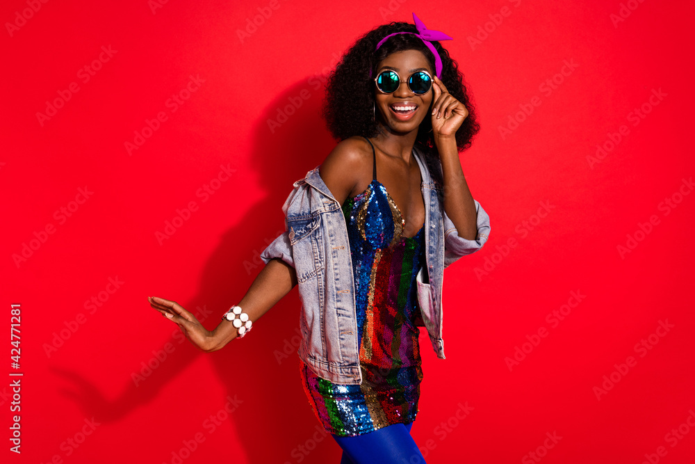 Photo of sweet pretty wavy dark skin lady wear pin up outfit arm glasses smiling dancing isolated red color background Photo of sweet pretty wavy dark skin lady wear pin up outfit arm glasses smiling dancing isolated red color background
