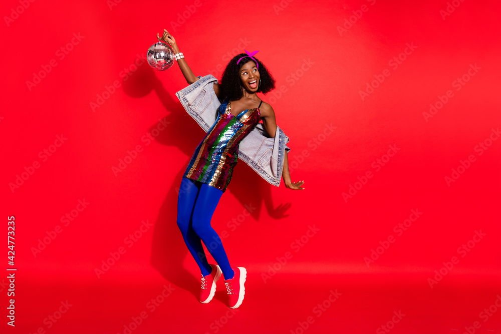 Photo of funky lady hold glowing ball dance look empty space wear dress headband isolated red color background Photo of funky lady hold glowing ball dance look empty space wear dress headband isolated red color background