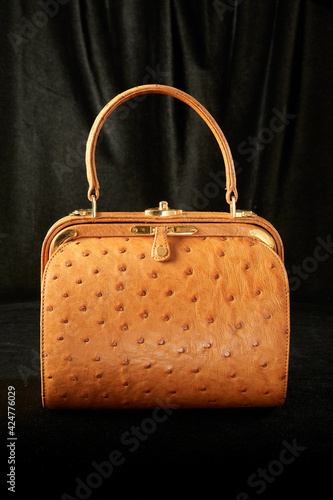 Women's orange ostrich leather handbag isolated on black background
