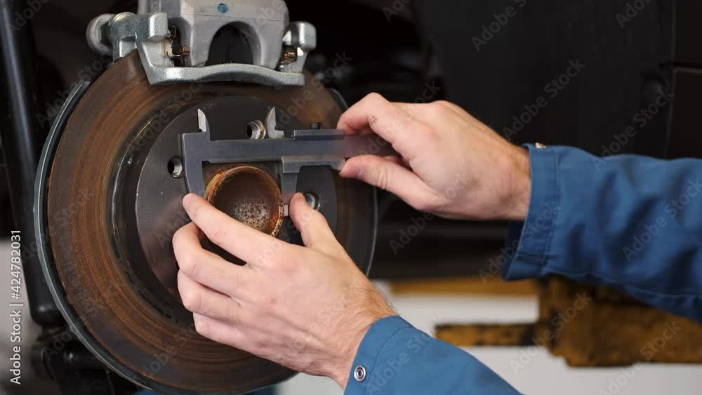 Focused repairman using tool to check car chassis Focused repairman using tool to check car chassis