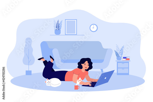 Happy cartoon woman chatting, working, surfing internet at home. Flat vector illustration. Girl doing remote work, lying on floor at cozy living room with laptop and cat. Freelance job concept