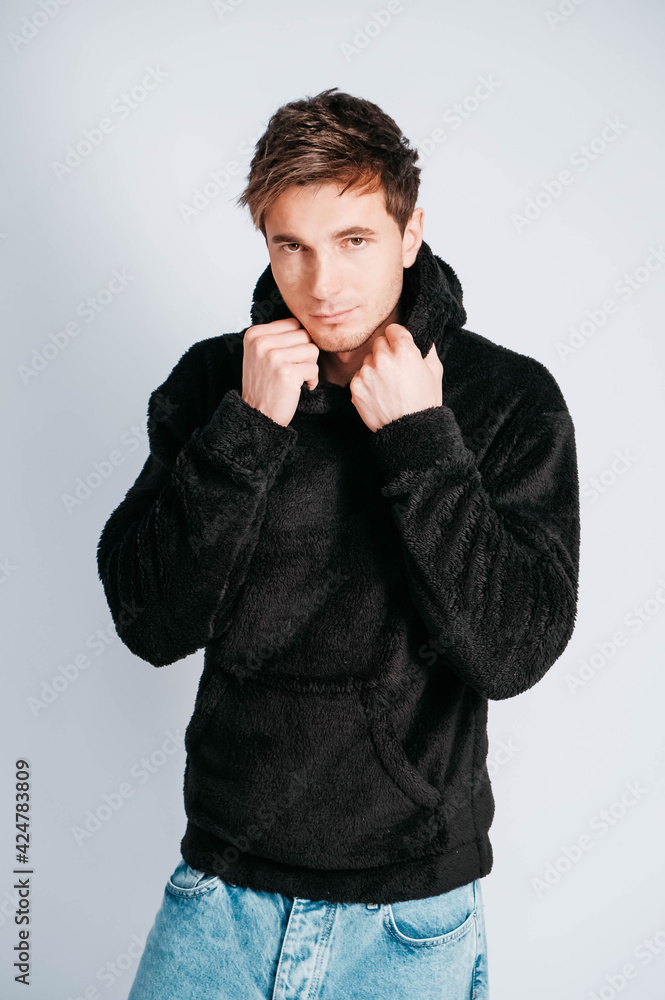 Young man in black sweatshirt with hood on a white background. Copy, empty space for text Young man in black sweatshirt with hood on a white background. Copy, empty space for text