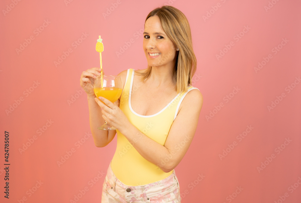 Picture of smiling young woman in swimwear isolated over pink background holding cocktail. Picture of smiling young woman in swimwear isolated over pink background holding cocktail.