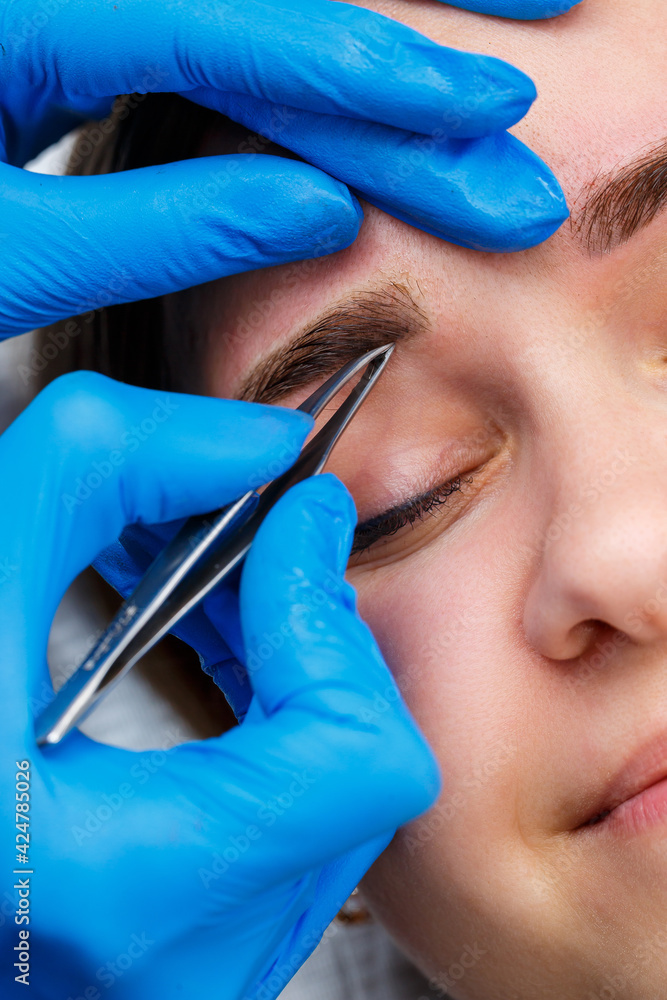 The master plucks out the excess hairs on the eyebrows with tweezers, giving them a shape. The master plucks out the excess hairs on the eyebrows with tweezers, giving them a shape.