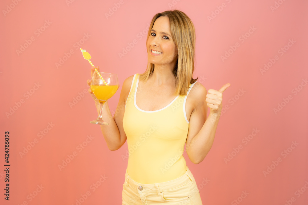 Picture of smiling young woman in swimwear isolated over pink background holding cocktail. Picture of smiling young woman in swimwear isolated over pink background holding cocktail.