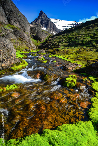 The boulders, crystal clear glacial streams and bright green moss of Stórurð watched by the jagged Dyrfjöll Mountains, Borgarfjörður Eystri, East Fjords, Iceland