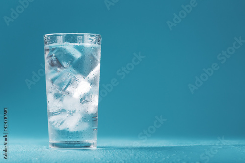 Ice cubes in a glass with crystal clear water on a blue background. photo
