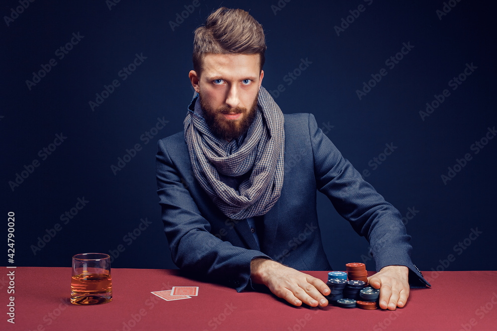 Stylish bearded Man in suit and scarf playing in dark casino, smoking cigar, drink whiskey Stylish bearded Man in suit and scarf playing in dark casino, smoking cigar, drink whiskey