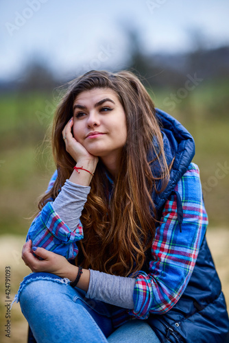portrait of a young woman wearing a hooded jacket with nature in the background