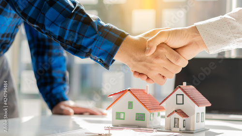 Real estate agent shakes hands with client after signing home purchase agreement after Finan has passed.