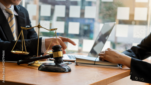 Good service, consultation of business women and male lawyers or judge advisors, having a team meeting with clients, legal concepts and a hammer with scales on the table.