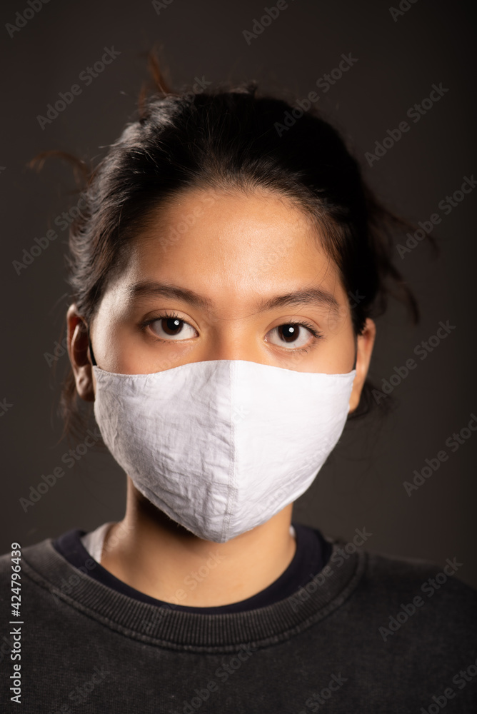 asian woman wearing a white mask in dark background