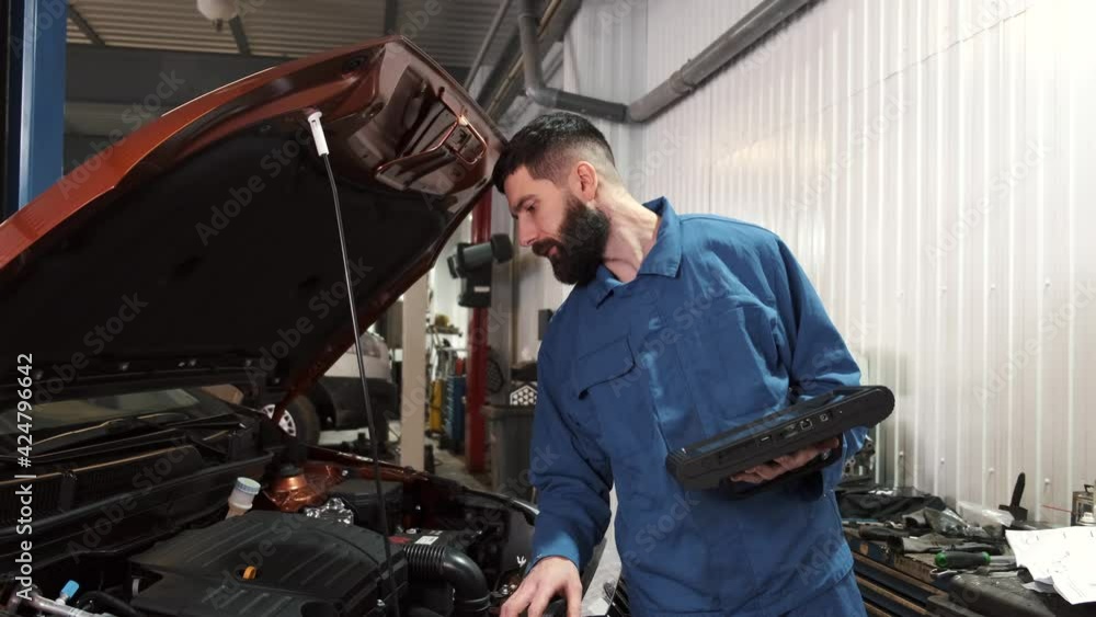 Professional auto mechanic examining car engine, looking under hood Professional auto mechanic examining car engine, looking under hood
