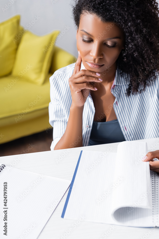 African american woman looking at notebook at table African american woman looking at notebook at table