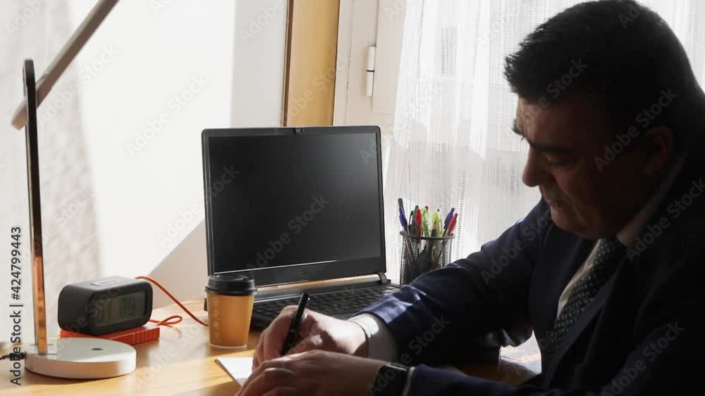 video of a manager working from home and taking notes on a sheet of data from the laptop video of a manager working from home and taking notes on a sheet of data from the laptop