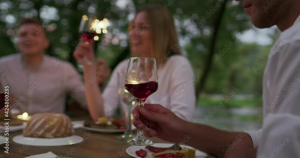 Youth friendship concept - Hands toasting red wine glass beside river at nightime Youth friendship concept - Hands toasting red wine glass beside river at nightime