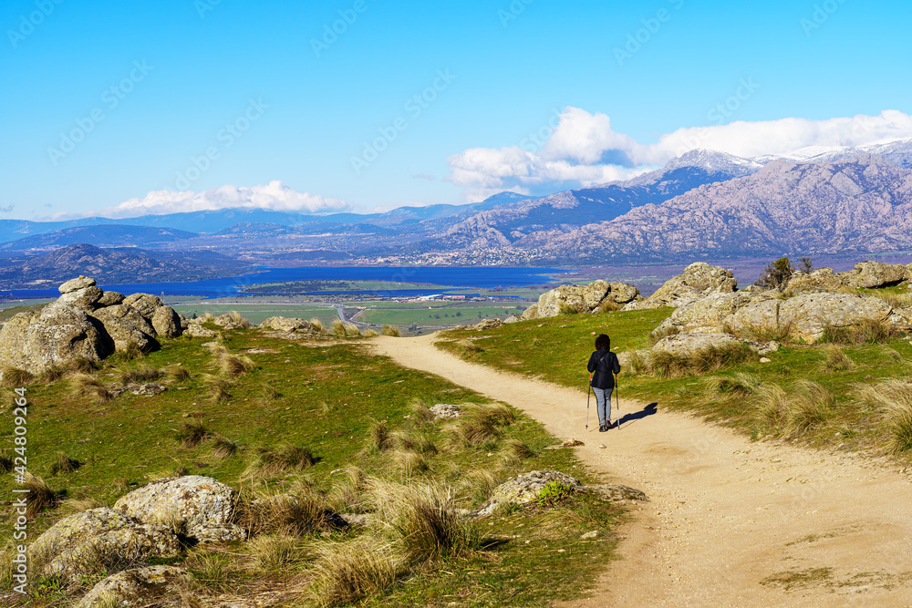 Woman hiking up the mountain paths to the top, with beautiful views of the landscape in the background.