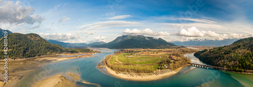 Aerial Panoramic View of a River in the valley surrounded by Canadian Mountain Landscape. Green Farms. Taken in Harrison Mills, Fraser Valley, East of Vancouver, BC, Canada.