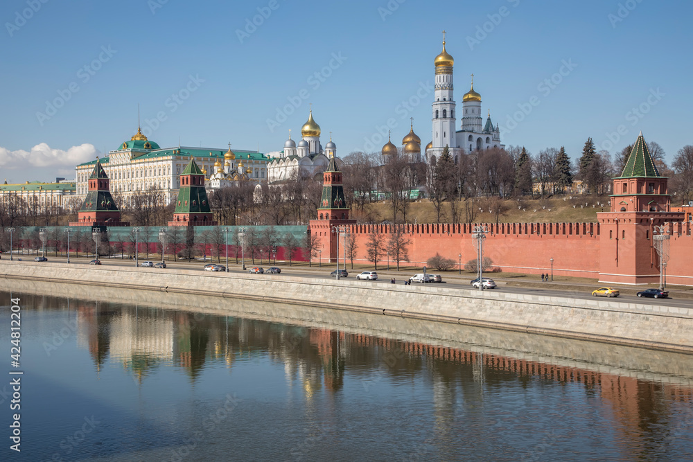 The beautiful Moscow Kremlin on the banks of the river. Red brick towers. Blue sky. Sunny day. Ancient architecture.