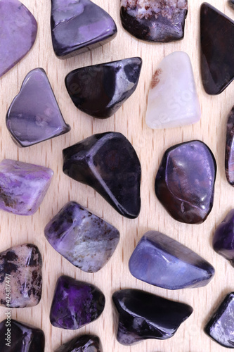 Sugilite rare jewel stones on light varnished wood texture. Sparse mineral pebbles background. photo