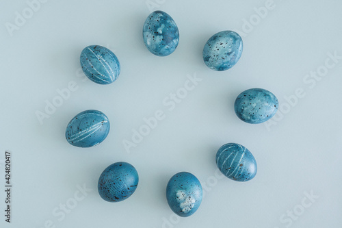 Minimalistic Easter flat lay of Easter eggs laid out in a circle on a light blue background with space for text, top view. Easter is coming soon. Spring Festival