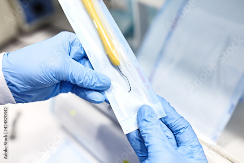 Sterilizing medical instruments in autoclave. Dental office. Close up dentist assistant's hands holding packaged with vacuum packing machine medical instruments ready for sterilizing in autoclave.