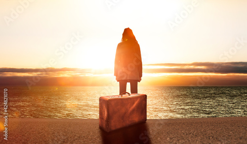 Junge Frau mit einem Koffer bei sonnenuntergang