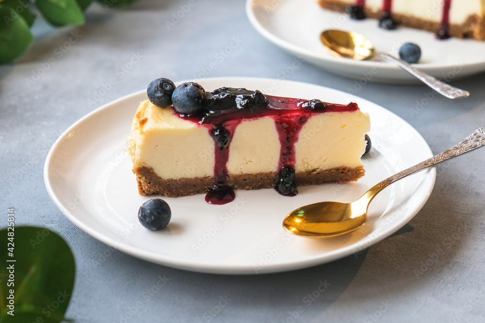 Portion of cheesecake poured blueberry jam decorated fresh blueberries. Delicious cheese pie on plate. Portion of cheesecake poured blueberry jam decorated fresh blueberries. Delicious cheese pie on plate.