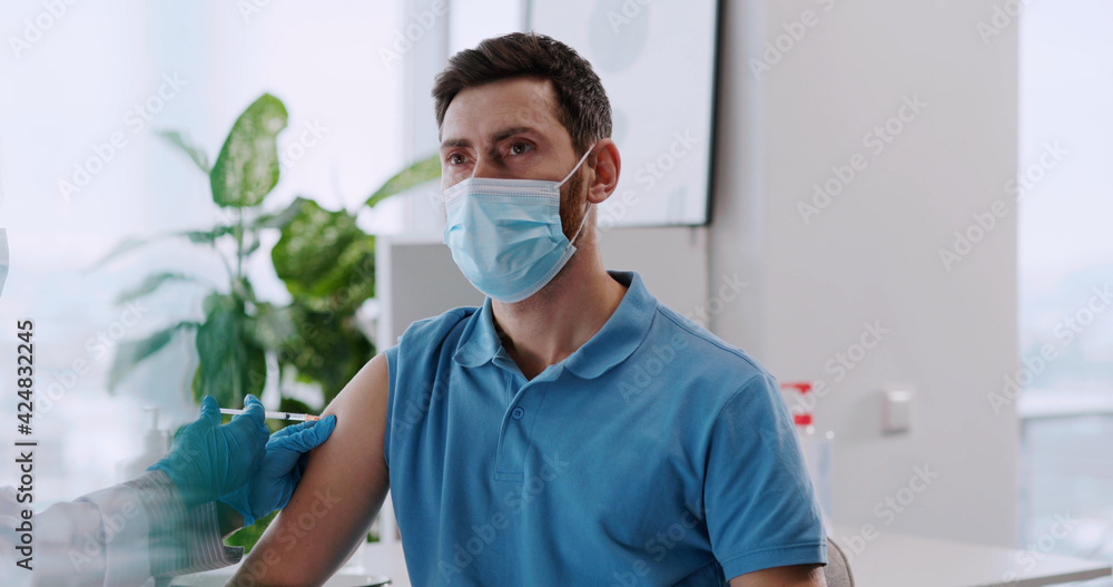 Young caucasian healthy man being injected with experimental vaccine against coronavirus covid-19 infection in medical hospital. healthcare concept. Young caucasian healthy man being injected with experimental vaccine against coronavirus covid-19 infection in medical hospital. healthcare concept.