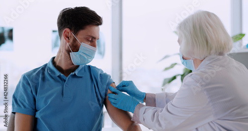 Young caucasian healthy man being injected with experimental vaccine against coronavirus covid-19 infection in medical hospital. healthcare concept.