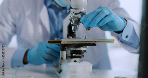 Doctor African American Laboratory Worker in Face Mask Using Microscope Examining Bacteria of Infection. Vaccine Development. Medical Employee.