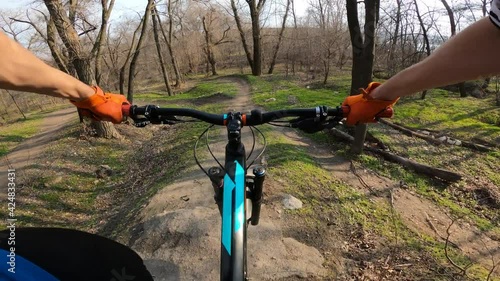 The cyclist rides along a forest trail with jumping jumps. First-person view.