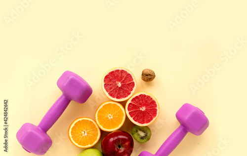 Healthy food and sports motivation concept. Top view of fresh citrus and pink dumbbells © Olena Poberezhna