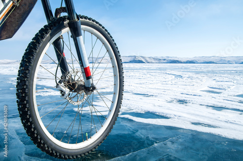 Bicycle on ice. Close-up of a studded bicycle tire on the background of an icy surface. Winter sport concept. © Sergey