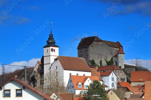 church close to a medieval castle in a village against blue sky