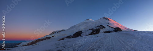 Panoramic view of Mt. Elbrus summits from its south slope at sunrise. Prielbrusie national park, Kabardino-Balkaria, Russia.