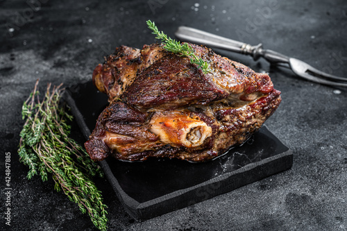Oven Roasted lamb mutton whole leg with thyme. Black background. Top view