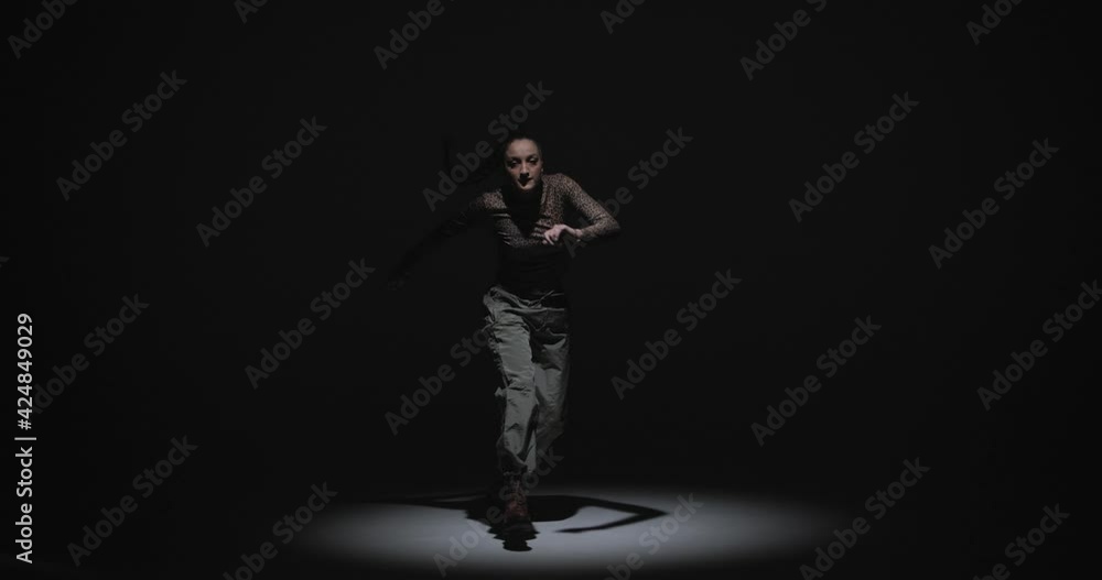 Expressive ethnic modern african female dance. Cool stylish girl dancing with passion and rhythm at spotlight in studio Expressive ethnic modern african female dance. Cool stylish girl dancing with passion and rhythm at spotlight in studio
