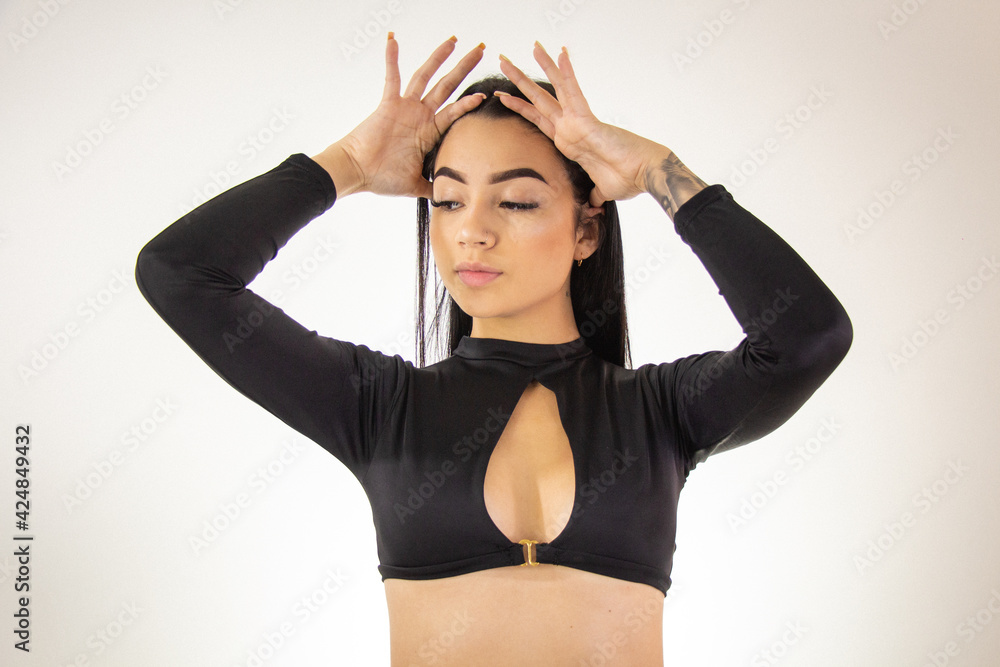 Foto de Mujer joven morena sexy vistiendo ropa juvenil de color negro,  hermosa chica con cabello negro largo y morena vistiendo blusa corta de  color negro do Stock