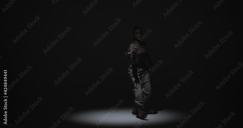 Cool dancing stylish girl in spotlight at studio. Ethnic african expressive dance of professional female performer Cool dancing stylish girl in spotlight at studio. Ethnic african expressive dance of professional female performer
