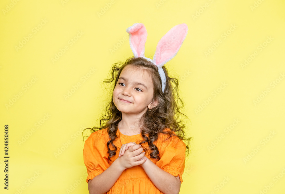 funny happy girl with easter bunny ears on yellow background