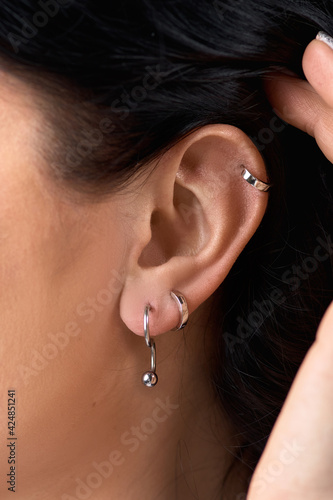 Deer stud earring on woman's ear close up. Piercing